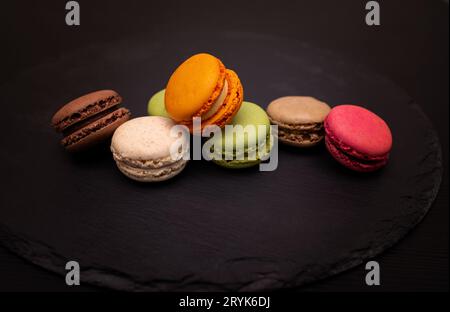 Colorful macaroni on a black slate background. Close-up in different positions placed. Stock Photo