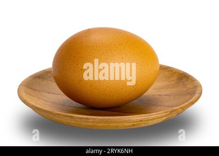 Single raw chicken egg in wooden plate isolated on white background. Stock Photo