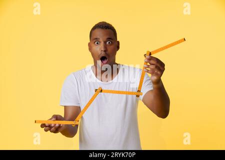 Concept of income growth, amazed African American man holding folding ruler and showing growth chart on the stock exchange. Man Stock Photo