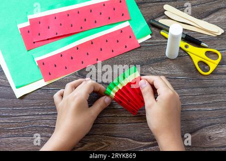 Instruction step 5. Paper Fan watermelon and origami paper ice cream on a wooden table. Childrens art project, handmade, crafts Stock Photo
