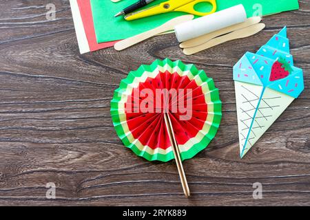 Paper Fan watermelon and origami paper ice cream on a wooden table. Childrens art project, handmade, crafts for children. Stock Photo
