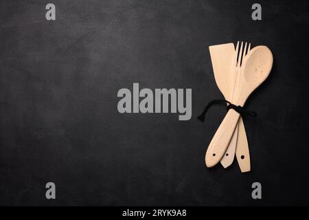 Fork and empty wooden spoon on a a black background, top view. Stock Photo