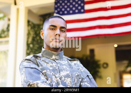 Portrait of biracial male american soldier wearing military uniform standing outside the house Stock Photo