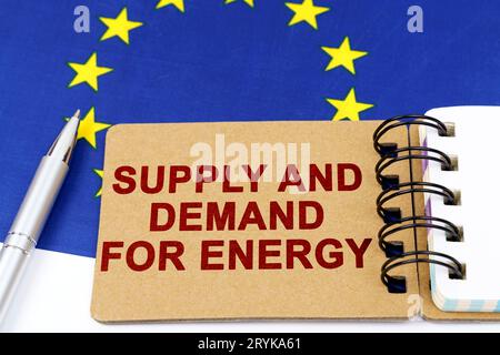 Economy and finance concept. On the flag of the European Union lies a pen and a notepad with the inscription - supply and demand for energy. Stock Photo