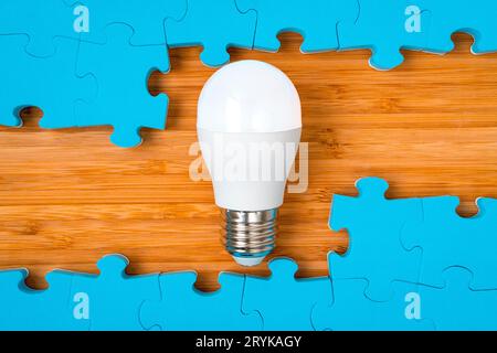 Blue puzzle frame with a bright light bulb in the middle Stock Photo