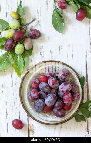 Seasonal food background. Ripe juicy plums in a bowl on a rustic wooden table. Top view flat lay. Copy space. Stock Photo