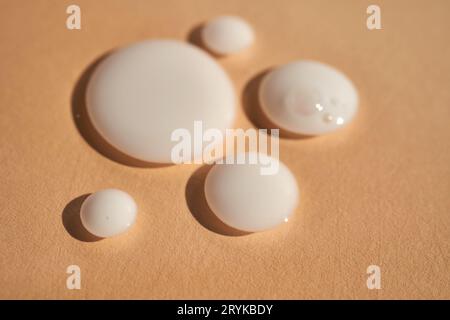 Drops of white milk on a beige background. Stock Photo