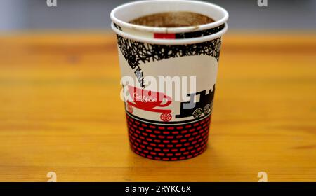 A drunk cup of Turkish coffee in a disposable drinking foam cup isolated on a wooden background, with text of coffee, cup and a train figure, Foam cup Stock Photo