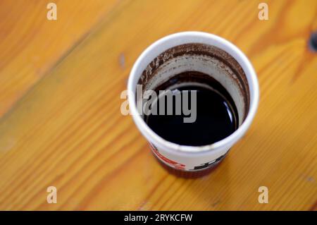 A drunk cup of Turkish coffee in a disposable drinking foam cup isolated on a wooden background, with text of coffee, cup and a train figure, Foam cup Stock Photo