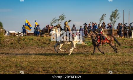 Horsman warriors, charging through a battlefield in front of fortifications, historical reenactment of Battle of Gniew Stock Photo