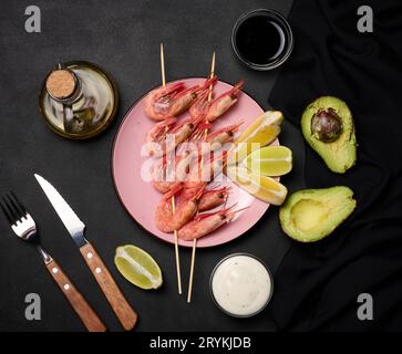 Shrimps strung on wooden sticks, soy sauce and spices on a black table, top view Stock Photo