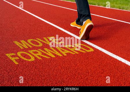 Man walk on the running track with a motivational quote written - MOVE FORWARD Stock Photo