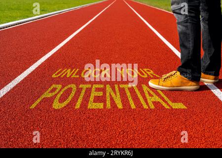 Man standing on the running track with a motivational quote written : Unlock Your Potential Stock Photo