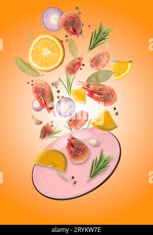 Pink plate and levitating shrimp with spices, lemon slices, rosemary on an orange background Stock Photo