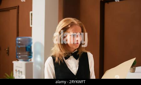 Hotel employee with check in documents reviewing room availability at exotic seaside resort, working with reservations. Front desk staff using archive forms to review bookings and accommodations. Stock Photo