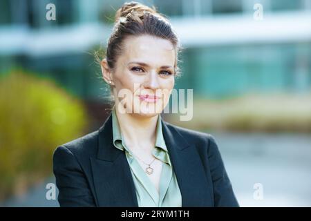 Portrait of sad modern 40 years old woman employee near office building in black jacket. Stock Photo