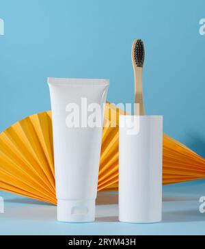 White plastic toothpaste tube and toothbrush on a blue background Stock Photo
