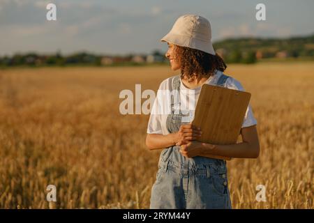 Smiling woman agronomist with clipboard in a wheat field checks the harvest. High quality photo Stock Photo