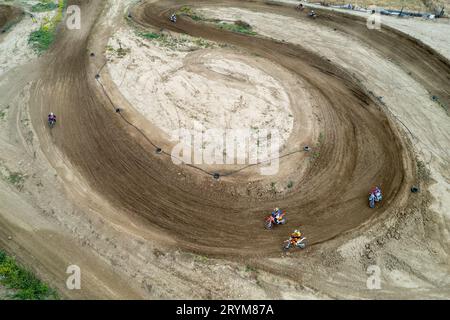 Drone aerial of a motocross race on a dirt curvy sport track. Aerial view of high-speed racing. Athletes in action Stock Photo