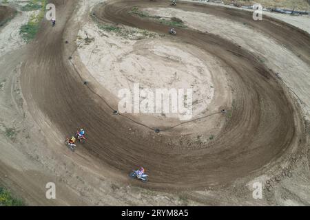 Drone aerial of a motocross race on a dirt curvy sport track. Aerial view of high-speed racing. Athletes in action Stock Photo