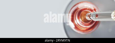 Oil or Serum bottle and pipette in petri dish on grey banner. Pink cosmetic product, selective focus Stock Photo