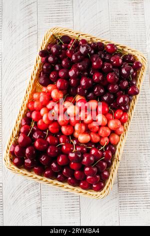 Ripe juicy cherries of different varieties in a wicker basket ...