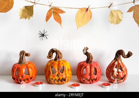 Halloween composition with ceramic pumpkins jack lantern and candles on table wall background. Home decoration Stock Photo