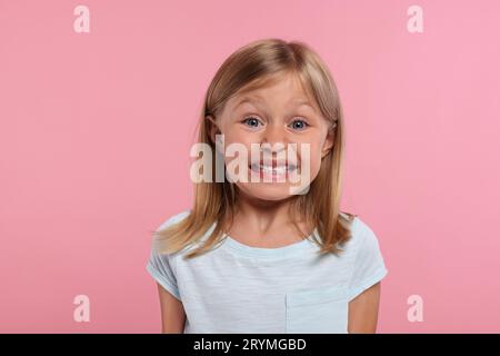 Embarrassment. Emotional little girl on pink background Stock Photo