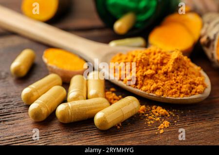 Aromatic turmeric powder and pills on wooden table, closeup Stock Photo