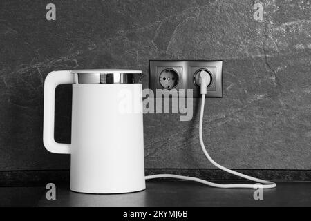 https://l450v.alamy.com/450v/2rymj6b/electric-kettle-plugged-into-power-socket-on-dark-grey-wall-indoors-2rymj6b.jpg