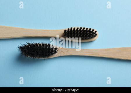 Two bamboo toothbrushes on light blue background, flat lay Stock Photo