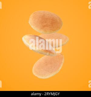 Tasty fresh pancakes falling on orange background Stock Photo