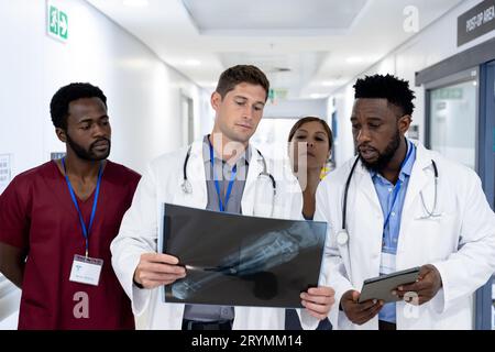 Diverse group of doctors discussing x ray walking in hospital corridor Stock Photo