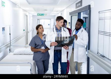 Diverse group of doctors discussing x ray walking in hospital corridor Stock Photo