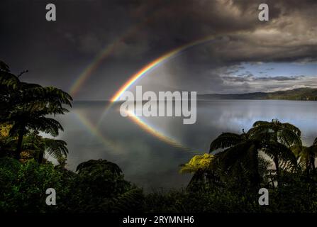 Double rainbow reflected in Lake Tarawera, ahead of approaching storm, Rotorua, New Zealand Stock Photo