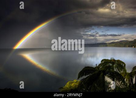 Double rainbow reflected in Lake Tarawera, ahead of approaching storm, Rotorua, New Zealand Stock Photo