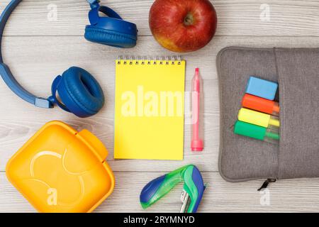 Bag-pencil case with color felt pens and marker, apple, notebook, headphones, stapler and lunch box. Stock Photo