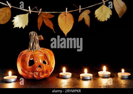 Halloween ceramic pumpkin jack lantern and candles on black background. Greeting card Stock Photo