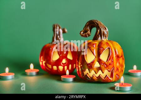Halloween composition with diy ceramic pumpkins jack lantern and candles on pine green background Stock Photo