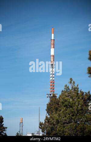 Communication tower on a building with 4G 5G antenna and satellite dish against blue sky. Mobile Com Stock Photo