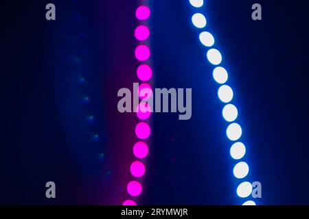 Pink and blue blurry neon bokeh lights on black. Abstract background of 80s colors Stock Photo