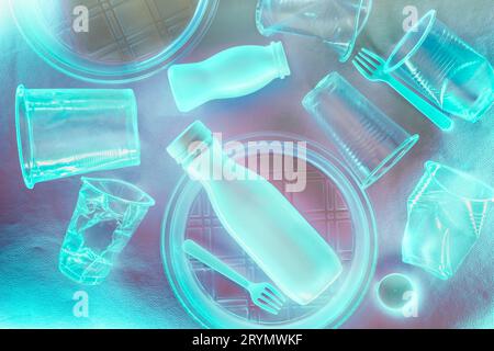 Plastic disposable tableware in blue neon lighting. Environmental pollution concept Stock Photo