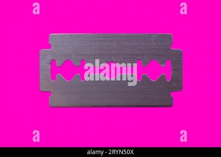 Razor blade against magenta background, symbol image, top view Stock Photo