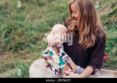 Cute mom hugs and toddler daughters. Family lifestyle in nature. Stock Photo