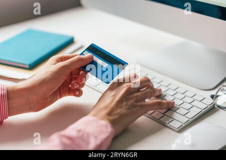 Close-up of a credit card in hands typing on a keyboard. Work from home. Online shopping with home delivery. Internet banking Stock Photo