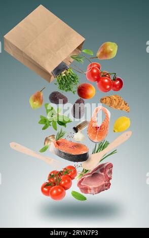 Fresh vegetables, fruits, salmon steaks and pork meat on the bone with spices fall from a brown paper bag. Buying groceries in a Stock Photo