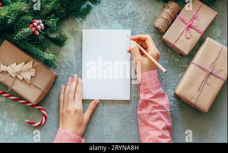 Writing goals for the next year. Women's hands write wishes on a white blank. Christmas content. Stock Photo