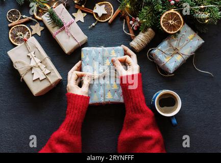 Elegant female hands tying twine on a wrapped Christmas present. Stock Photo