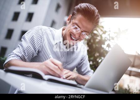 Smart attitude. Positive handsome man using a laptop and sitting in the cafe while surfing the internet. Young blogger or journa Stock Photo