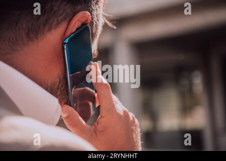 A businessman using his smartphone outdoors, showcasing the seamless integration of technology and mobility in modern profession Stock Photo